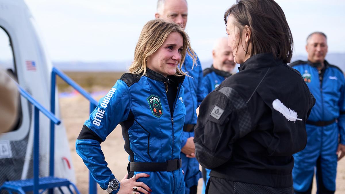 Karsen Kitchen in an astronaut uniform smiling as she speaks with a woman.